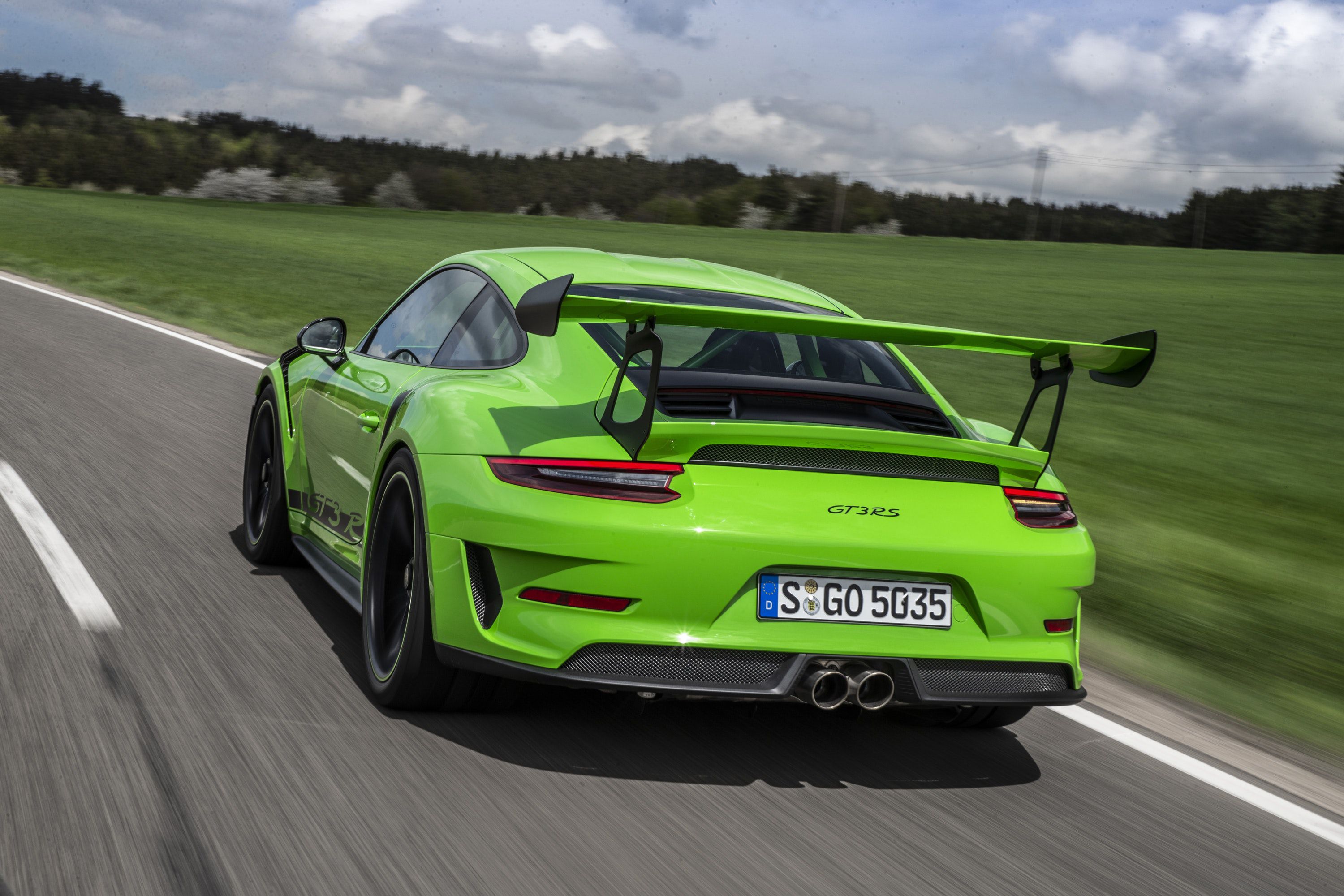 rear view of green porsche driving on a road